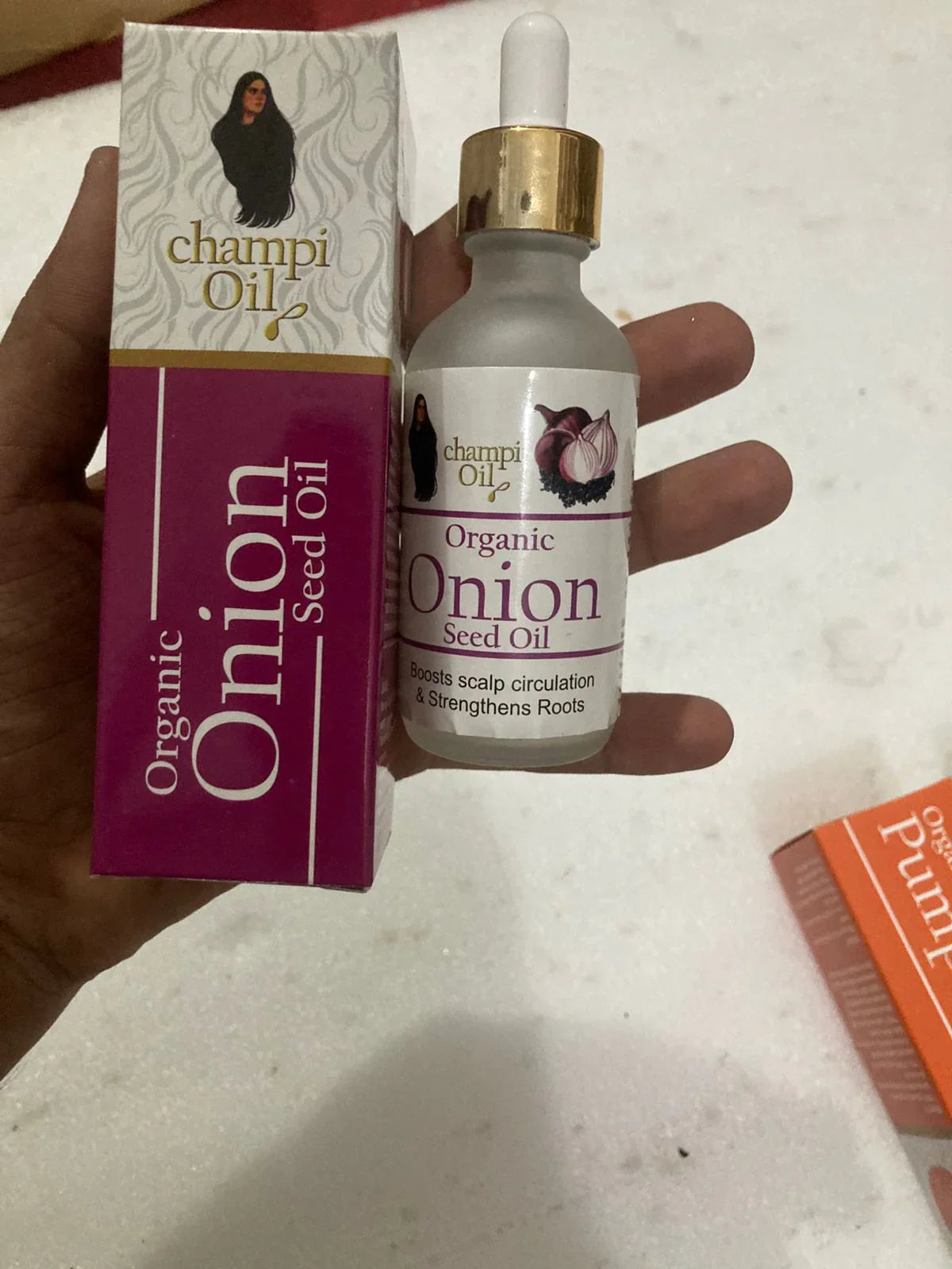 Champi Organic Onion Seed Oil bottle and packaging held in a hand