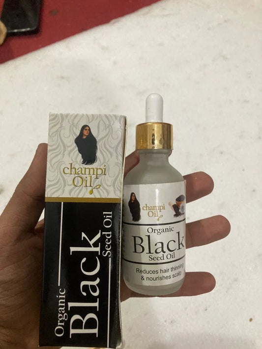 Organic Black Seed Oil bottle and packaging held by a hand on a light background