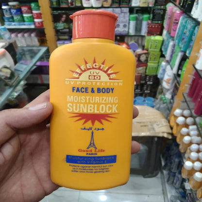 Hand holding a yellow sunblock bottle with an orange cap in a store setting