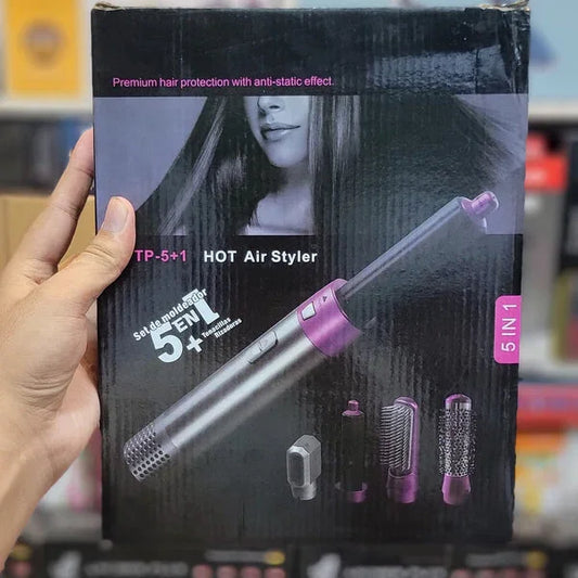 Hand holding a black hair dryer packaging with purple accents in a store setting.