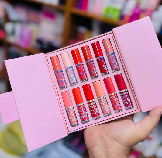 Set of red lip glosses in a pink box held by a hand with a blurred background